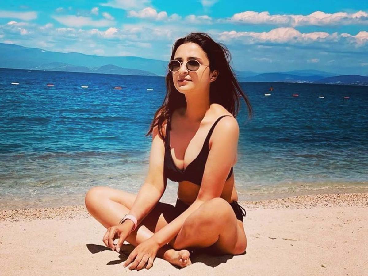 Bikini girl sitting cross legged on beach